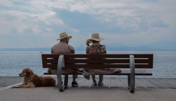 Elderly couple sat on a bench looking out to sea