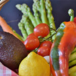 vegetables in a basket asparagus, tomatoes, avocado, pepper, lemon